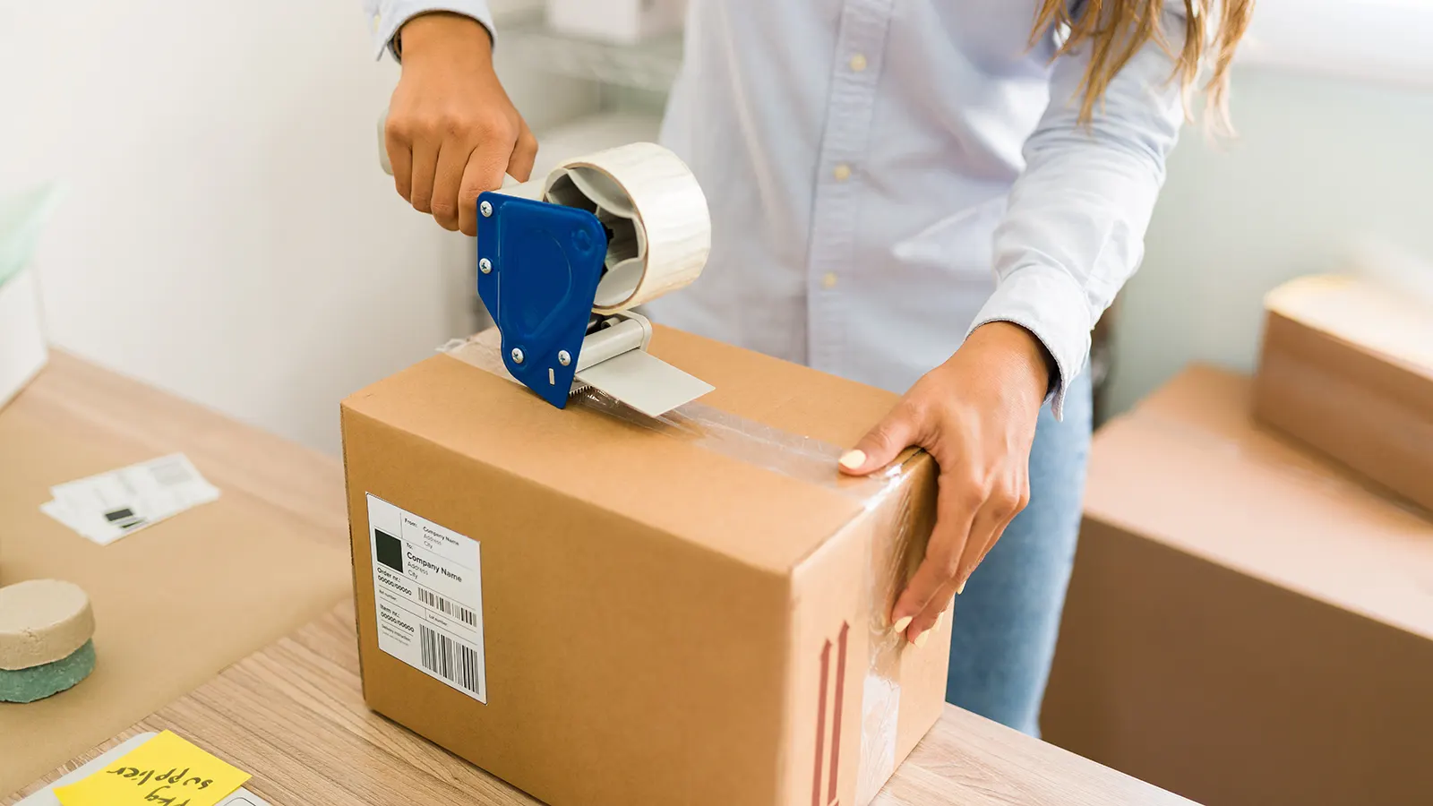 mujer cerrando paquete con cinta
