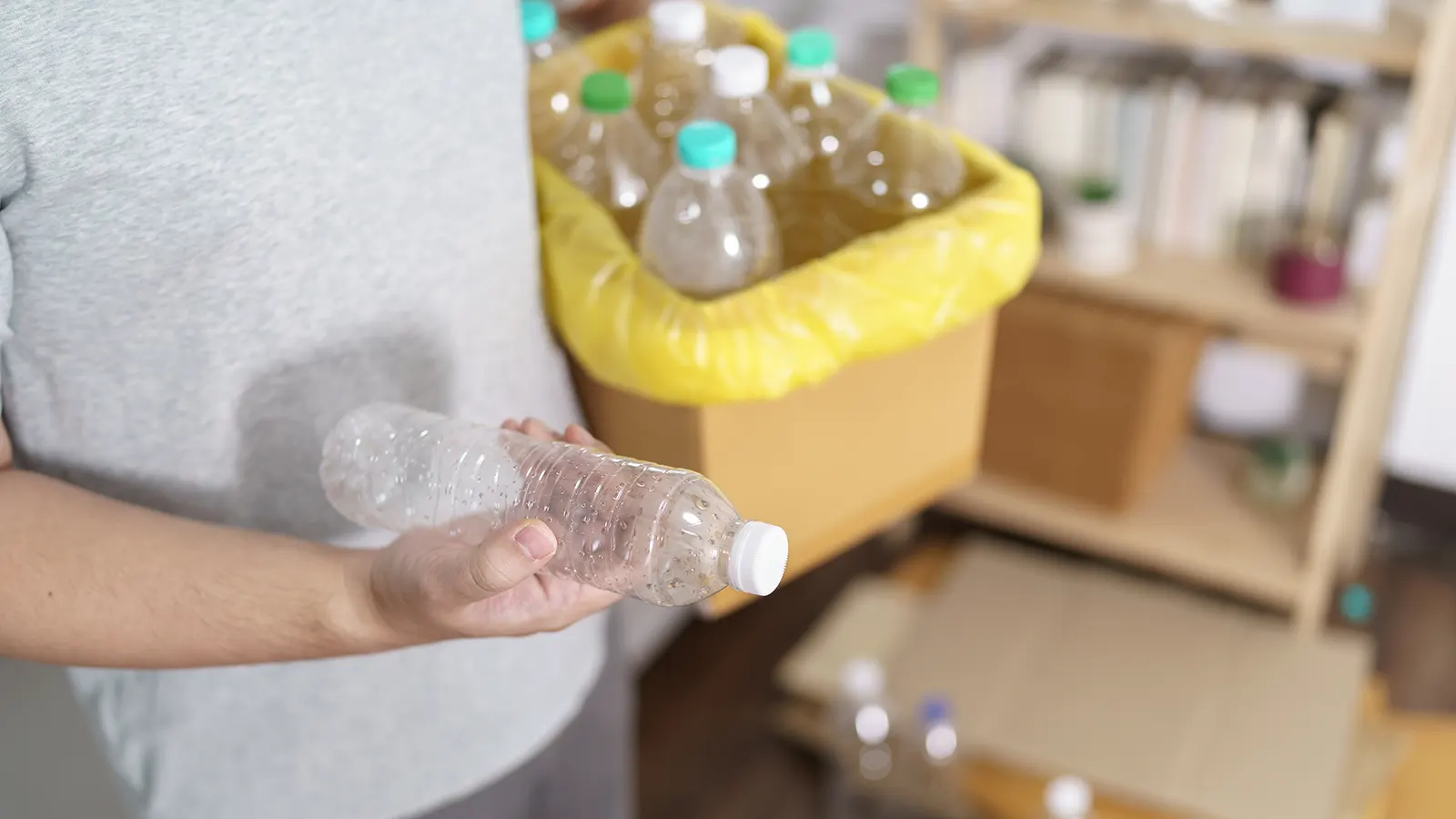 hombre con caja de botellas de plástico vacías para desechar