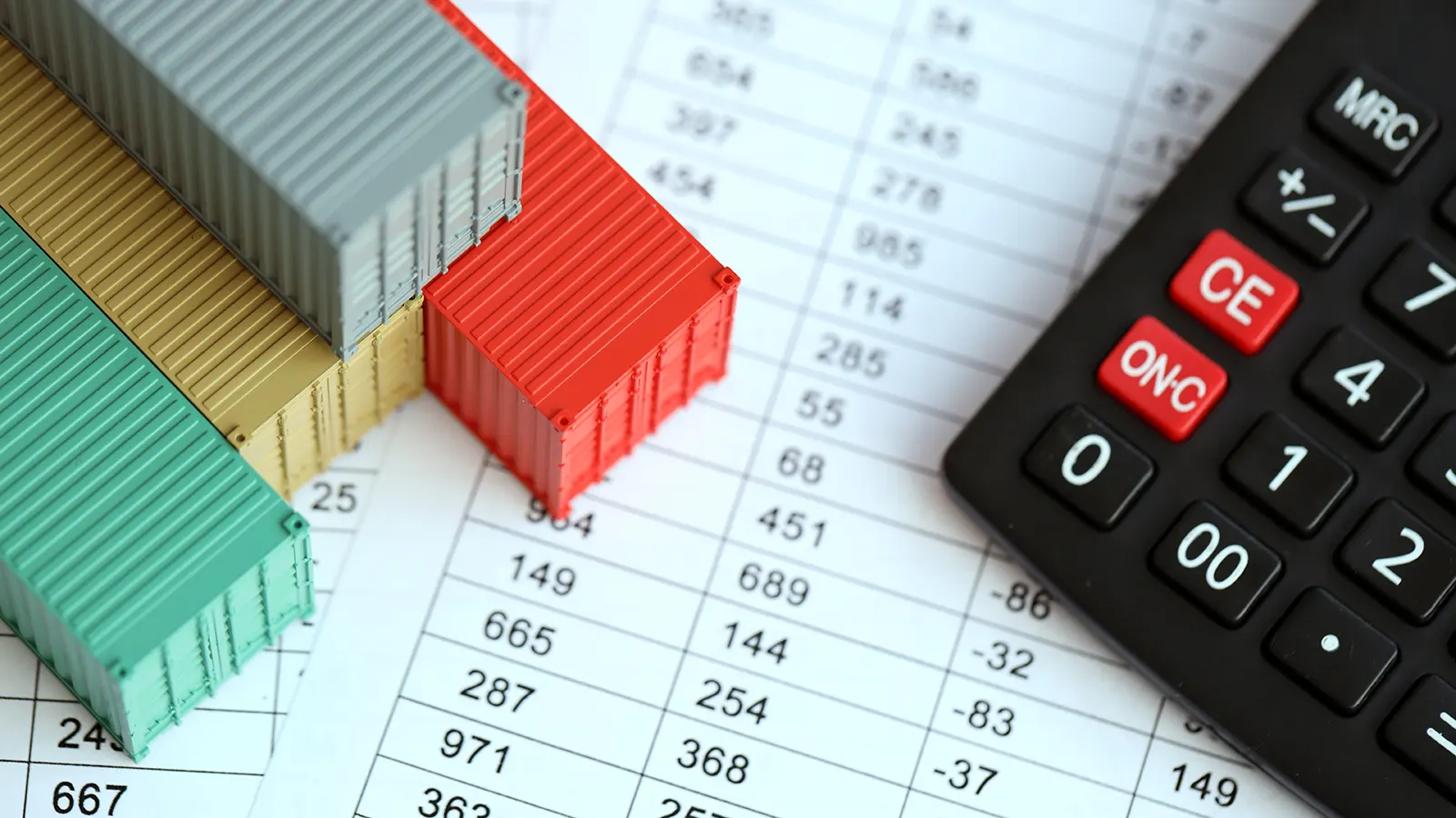 mini contenedores sobre una planilla de números junto a una calculadora